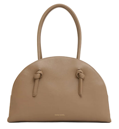 The Fortuna Bowling Bag by Mansur Gavriel features taupe Italian leather, a rounded top, two handles, knotted strap details, and a gold embossed logo near the base.