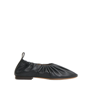 The Mansur Gavriel Ruched Ballerina is a black Italian leather flat featuring a gathered design, pull-tab at the heel, padded insoles, and a low-profile sole, shown in side view on a white background.