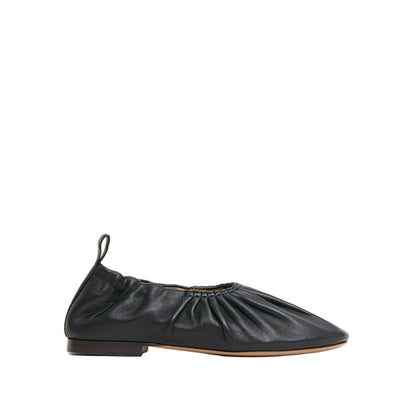 The Mansur Gavriel Ruched Ballerina is a black Italian leather flat featuring a gathered design, pull-tab at the heel, padded insoles, and a low-profile sole, shown in side view on a white background.