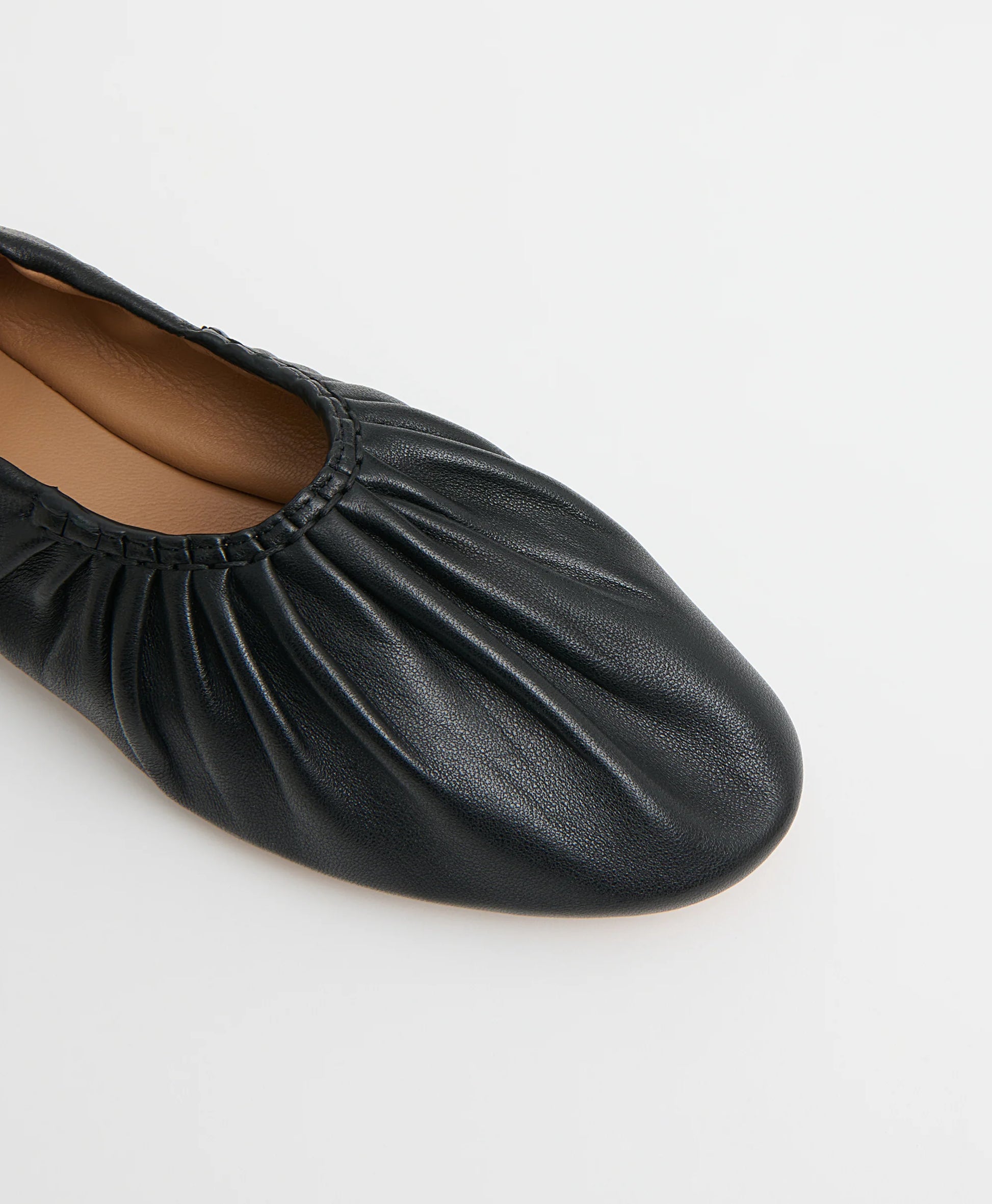 A close-up of the Mansur Gavriel Ruched Ballerina, a black Italian leather shoe featuring gathered detailing on the upper and a rounded toe, displayed against a plain white background.