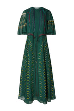 The Thessaly Dress by Altuzarra is a long, green silk dress with short sleeves and a tie waist, featuring an elegant leaf-patterned design in yellow, blue, and brown tones on the front and sleeves—an exquisite piece inspired by classic Italian style.
