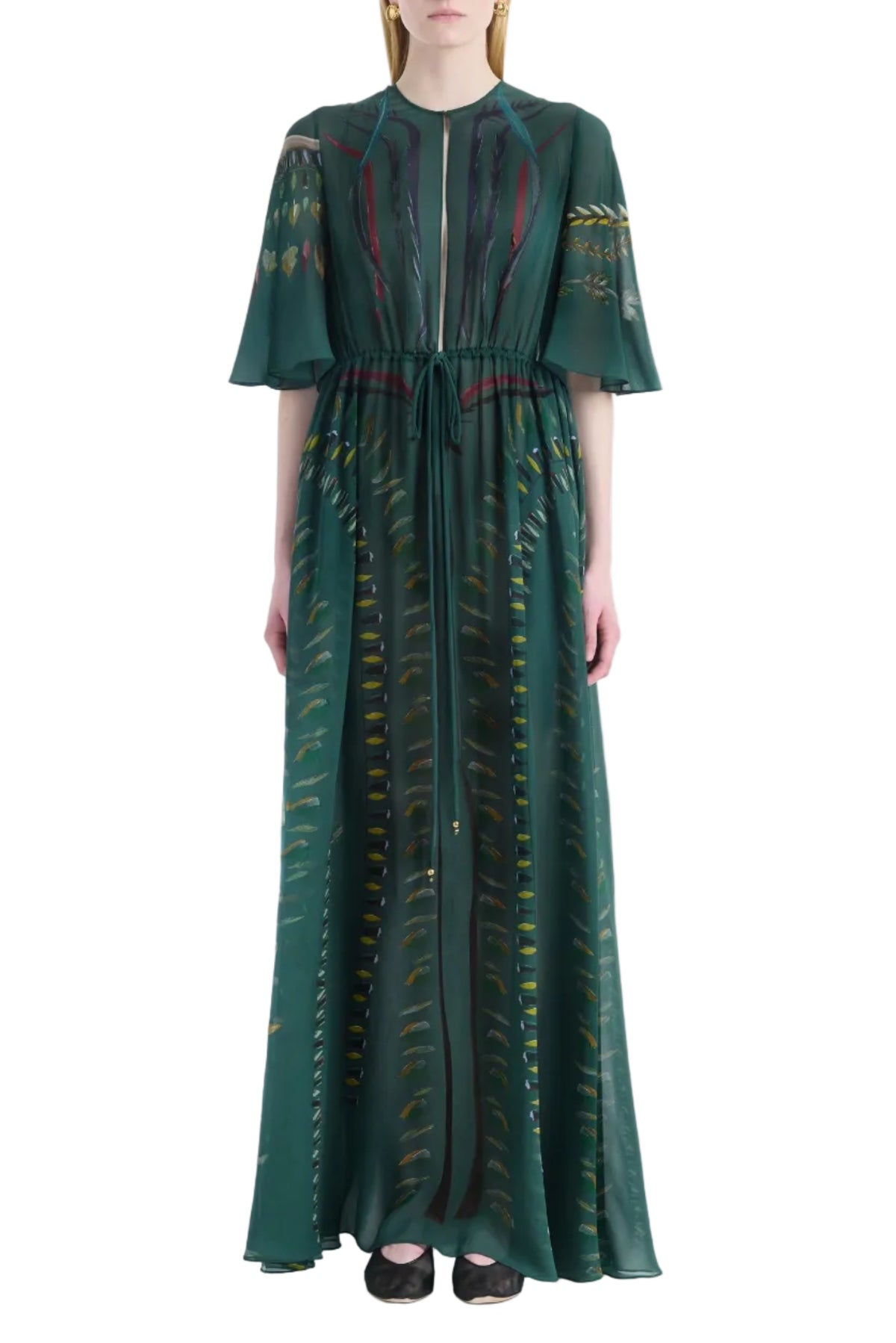 A model stands against a white background wearing the Altuzarra Thessaly Dress, a floor-length, dark green piece featuring short sleeves, a tie waist, and a subtle patterned design.