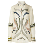 The Chika Top by Altuzarra is a long-sleeved cream blouse adorned with abstract botanical embroidery in earthy tones across the front, collar, sleeves, and cuffs. This relaxed design features a concealed button closure for a seamless finish.