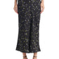 A person wearing the Altuzarra Casey Skirt—a black midi skirt featuring a small floral print and a streamlined silhouette—paired with black strappy sandals.