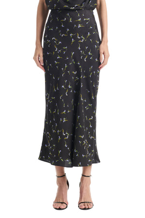 A person wearing the Altuzarra Casey Skirt—a black midi skirt featuring a small floral print and a streamlined silhouette—paired with black strappy sandals.