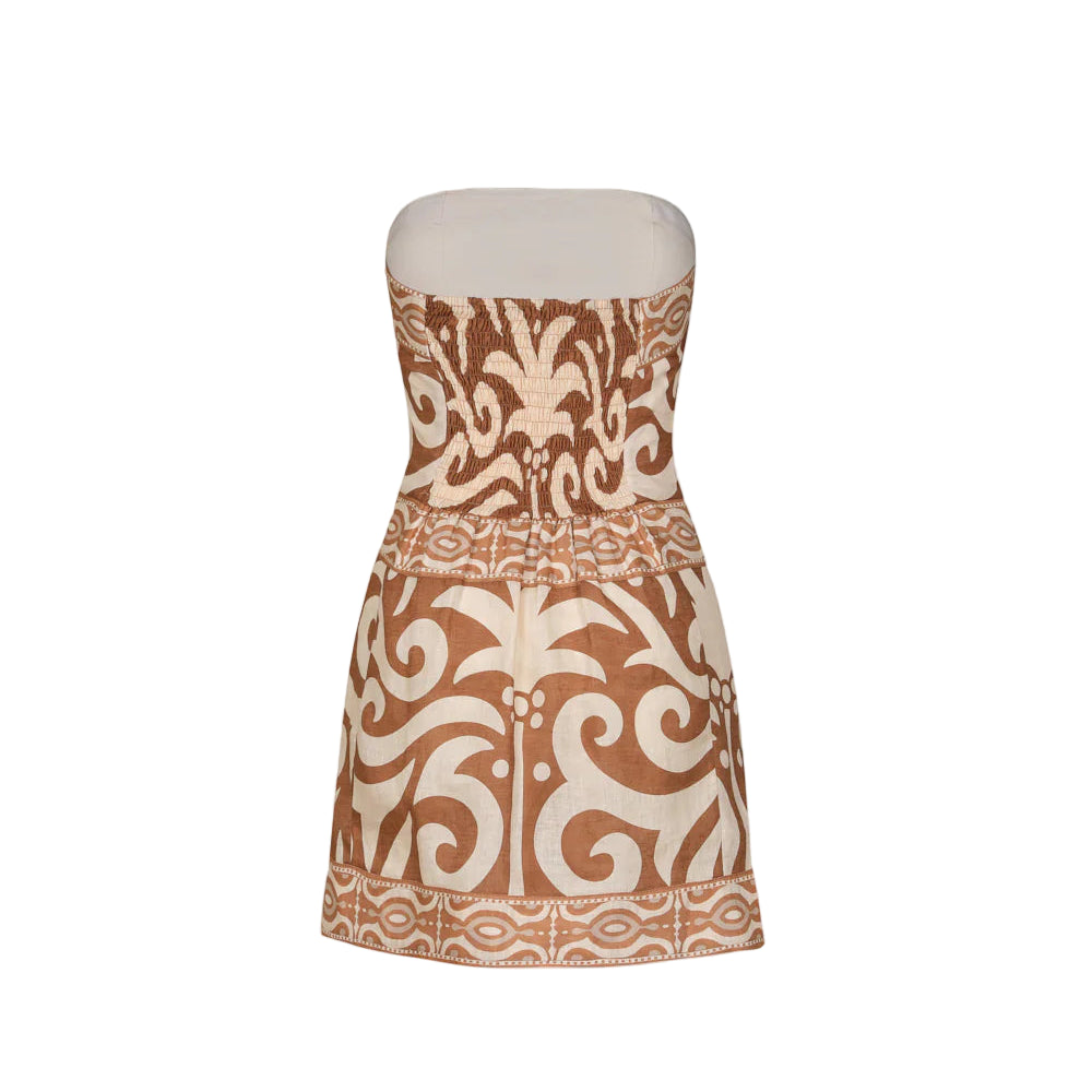 The Raiz Ritual Mini Dress by Johanna Ortiz is a strapless linen mini with a fitted bodice, wrap-effect skirt, and a brown and beige tribal-inspired JO print on crisp white.