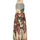 The Western Elements Ankle Dress by Johanna Ortiz is a sleeveless beige halter style with a hood, sheer back panel, and botanical green and brown palm tree print with scattered star designs, shown from the back.