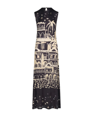 The Cardinal Direction Ankle Dress by Johanna Ortiz is a sleeveless, ankle-length shiny jersey dress with a beige architectural and palm tree landscape print on the front.