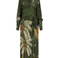 The Eternity Begins Wrap Dress by Johanna Ortiz is a long-sleeved, dark green silk crêpe de chine wrap dress with a tropical palm tree and star JO print, waist tie, and decorative hem border.