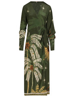 The Johanna Ortiz Eternity Begins Wrap Dress is a dark green silk crêpe de chine wrap dress with long sleeves, a JO tropical palm tree and star print, and a tie waist detail.