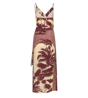 The Nouvel Arome Maxi Dress by Johanna Ortiz features a sleeveless, V-neck design with thin straps and a cream base adorned with maroon palm tree prints.