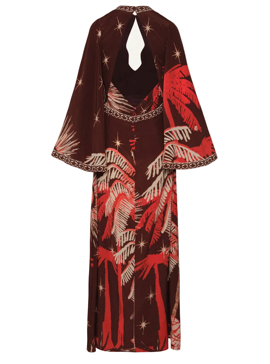 The Johanna Ortiz Leyenda Del Tiempo Maxi Dress features long sleeves, a keyhole back cutout, and a bold tropical palm print in red and beige with star accents.