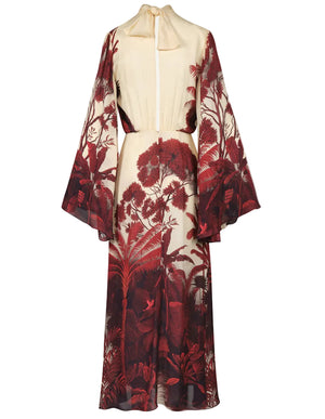 The Maiden Voyage Ankle Dress by Johanna Ortiz is an elegant silk georgette gown with long flared sleeves, a high neck, and a red botanical jungle print inspired by Colombian landscapes on the lower half.