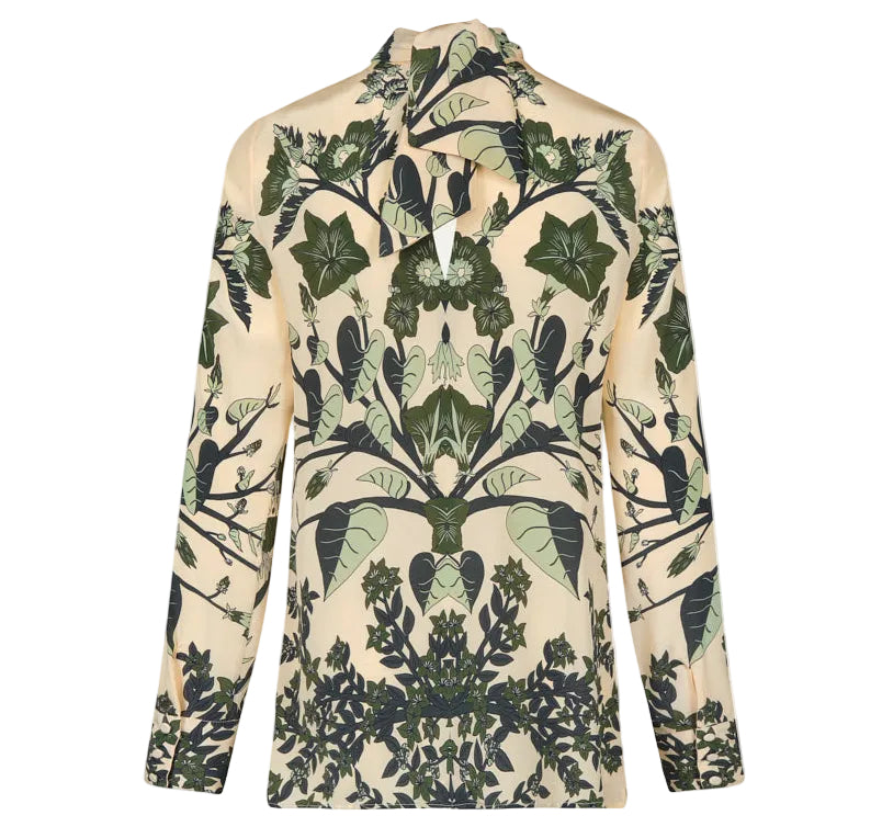 The Heavenly Garden Top by Johanna Ortiz is a cream silk long-sleeve blouse with a symmetrical green and dark leaf print, high pointed collar, and keyhole neckline.