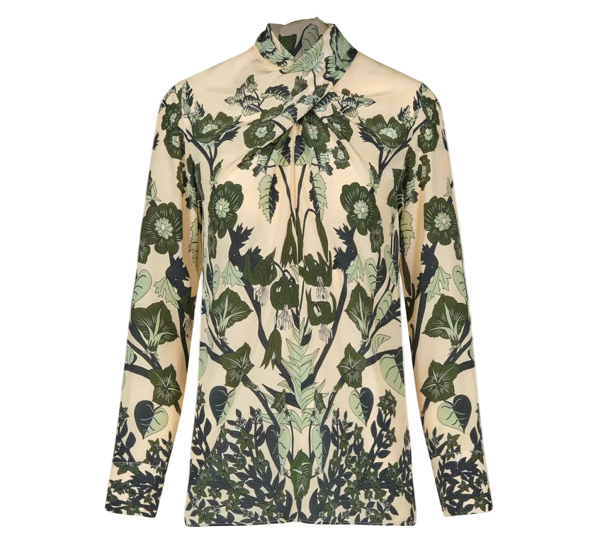 The Heavenly Garden Top by Johanna Ortiz is a long-sleeved cream silk CDC blouse with a high neck, adorned with the brand’s signature green botanical leaf and flower motif.