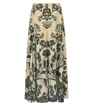 The Poems of the Sea Ankle Skirt by Johanna Ortiz features a beige botanical print with symmetrical green leaf motifs and an A-line silhouette, displayed against a white background.