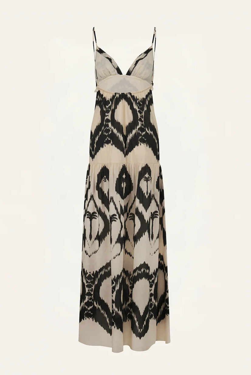 The Zea Palm Maxi Dress by Johanna Ortiz is a sleeveless beige cotton poplin maxi dress with a black abstract pattern, thin adjustable straps, and an elegant empire waist, shown on a plain background.