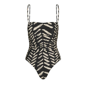 The Whispering Tides One Piece by Johanna Ortiz is a black one-piece swimsuit with thin straps, adorned with an abstract beige brushstroke JO print.