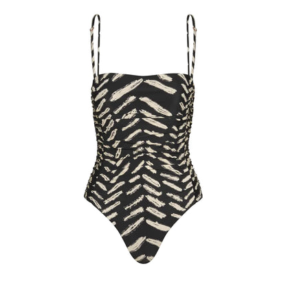 The Whispering Tides One Piece by Johanna Ortiz is a black one-piece swimsuit with thin straps, adorned with an abstract beige brushstroke JO print.