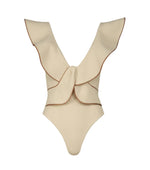 The Crinkle Beaches One Piece by Johanna Ortiz is a cream-colored crinkle lycra swimsuit with wide ruffled straps, brown edging, and a large decorative bow on the back—an elegant choice for the beach.