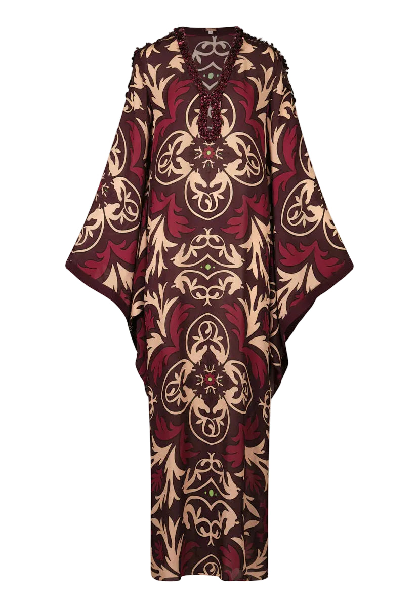 Introducing the One Palm Only Tunic Dress by Johanna Ortiz—a relaxed, floor-length silhouette with wide sleeves, adorned in an intricate maroon, beige, and brown pattern. This piece features a v-neckline embellished with hand-applied beaded detailing for a distinctive decorative touch.