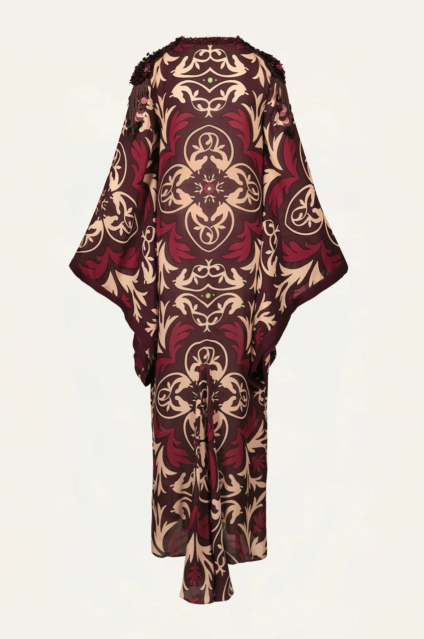 One Palm Only Tunic Dress by Johanna Ortiz featuring long sleeves and a floor-length silhouette, adorned with a maroon and beige baroque floral pattern and subtle Equine Mola motif accents, shown from the back against a plain light background.