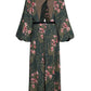 Back view of the Johanna Ortiz Golden Vibe Dress, a floor-length, long-sleeved silk crepe de chine gown in a dark green botanical print with a high neckline and a cutout back.