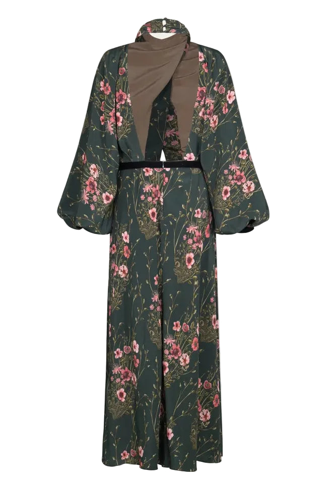 Back view of the Johanna Ortiz Golden Vibe Dress, a floor-length, long-sleeved silk crepe de chine gown in a dark green botanical print with a high neckline and a cutout back.