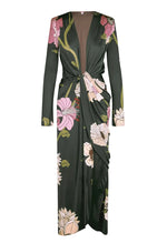 Johanna Ortiz Reinvention Oasis Ankle Dress: a dark green, ankle-length, long-sleeved shiny jersey dress with a pink and white botanical motif, deep V-neck, and knotted front detail.