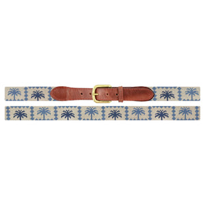 The Smathers & Branson Palms Belt features a beige needlepoint design with blue palm trees, brown Italian leather at the buckle area, and a brass buckle, shown laid flat on a white background.