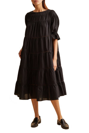 A person wearing a Merlette New York Merlette Paradis Dress with short sleeves, featuring OEKO-TEX® certified cotton lace trim, paired with black loafers.