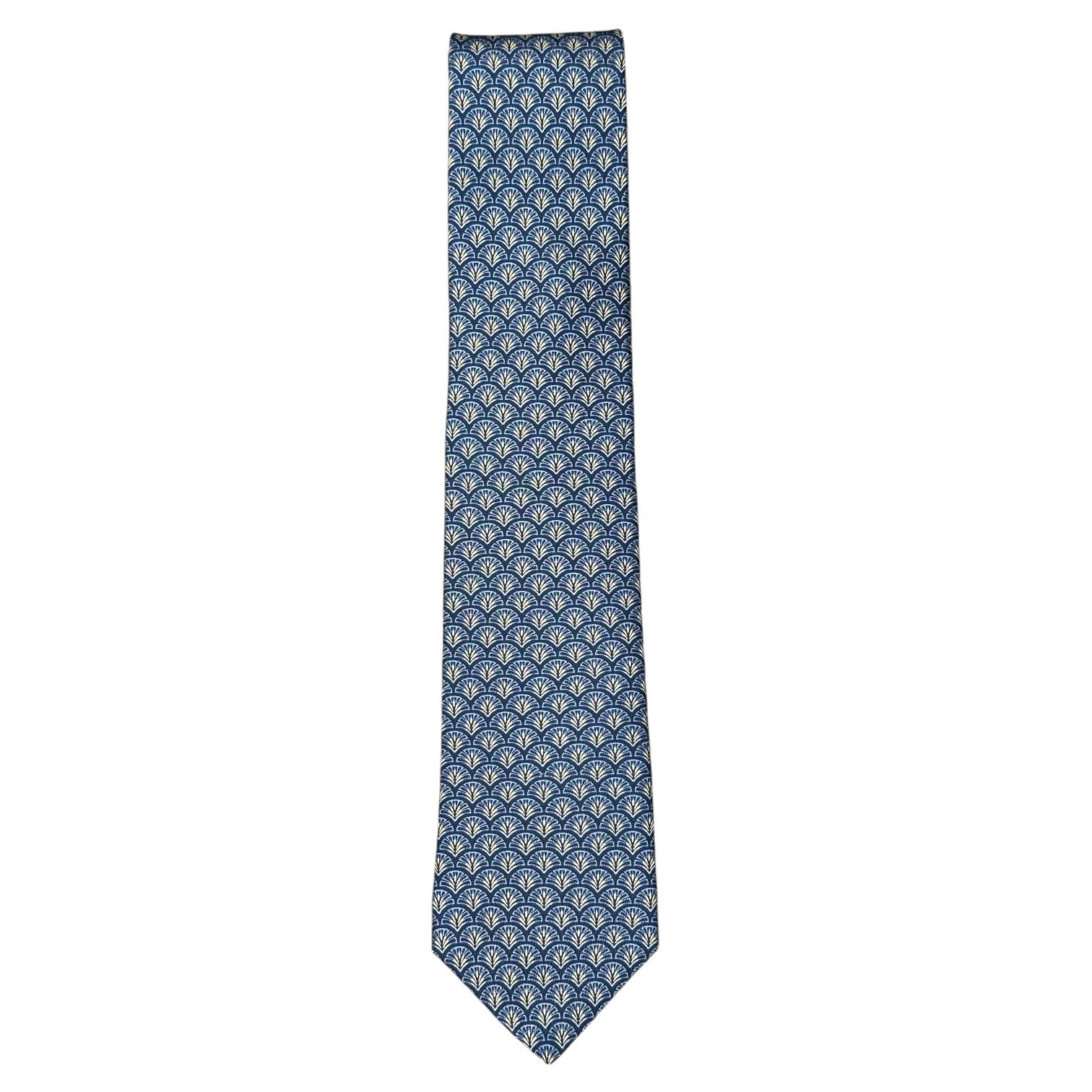 The Robert Jensen Peacock Motif Tie is a blue silk tie with a repeating light blue and white peacock-inspired design, shown against a white background.