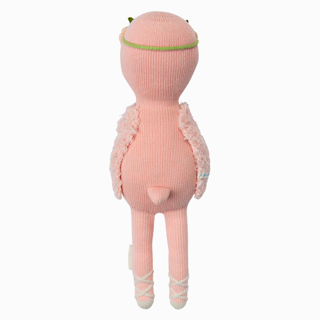 Penelope the Flamingo by Cuddle + Kind is a 13" pink knitted stuffed animal with fuzzy arms, a small tail, and ballet shoes, shown standing upright from behind—an adorable birthday gift that brings joy and warmth to any celebration.
