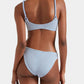A woman models the Hunza G Phoebe Bikini, featuring light blue crinkle fabric and braided straps, shown from the back against a plain light background.
