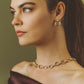 A person wearing an Anabel Aram Neptune Chain Necklace with interlocking gold oval links and matching small hoop earrings.