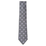 The Starburst Tie by Robert Jensen is a gray silk tie, hand-stitched in Italy, featuring a small checkered pattern with repeating white and blue circular floral motifs.