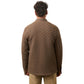 A man faces away from the camera, dressed in Faherty’s Epic Quilted Fleece in brown with beige pants, set against a white background.
