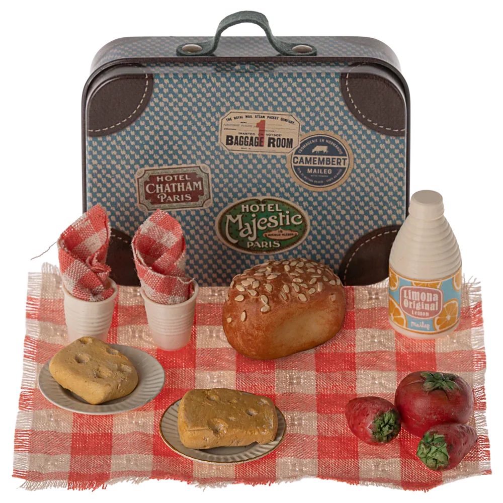 The Maileg Picnic Set by Maileg features a charming collection of a small vintage-style metal suitcase and assorted miniature food items, including bread, tomatoes, drinks, napkins, and plates, all arranged on a red and white checkered cloth.