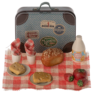 The Maileg Picnic Set by Maileg features a charming collection of a small vintage-style metal suitcase and assorted miniature food items, including bread, tomatoes, drinks, napkins, and plates, all arranged on a red and white checkered cloth.