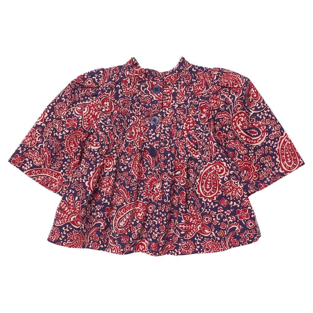 The Pink Chicken Girls’ Jaipur Top is a long-sleeved baby shirt showcasing a red and white paisley pattern on a dark blue background, accented with navy glitter buttons at the front and a gathered waist.