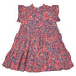 The Girls’ Jennifer Dress by Pink Chicken features short sleeves with ruffles, a red and white paisley vines pattern on a blue background, and a slightly flared, tiered skirt.