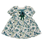 Pink Chicken Girls’ Hermione Dress for a holiday party, featuring a green holly leaf and berry print with three stacked velvet bows at the neckline.