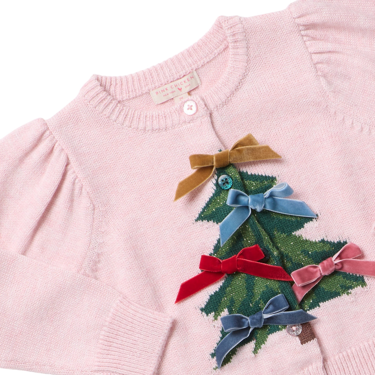 Girls’ Constance Sweater in light pink knit, featuring a green Christmas tree design decorated with small velvet bows and glitter buttons.