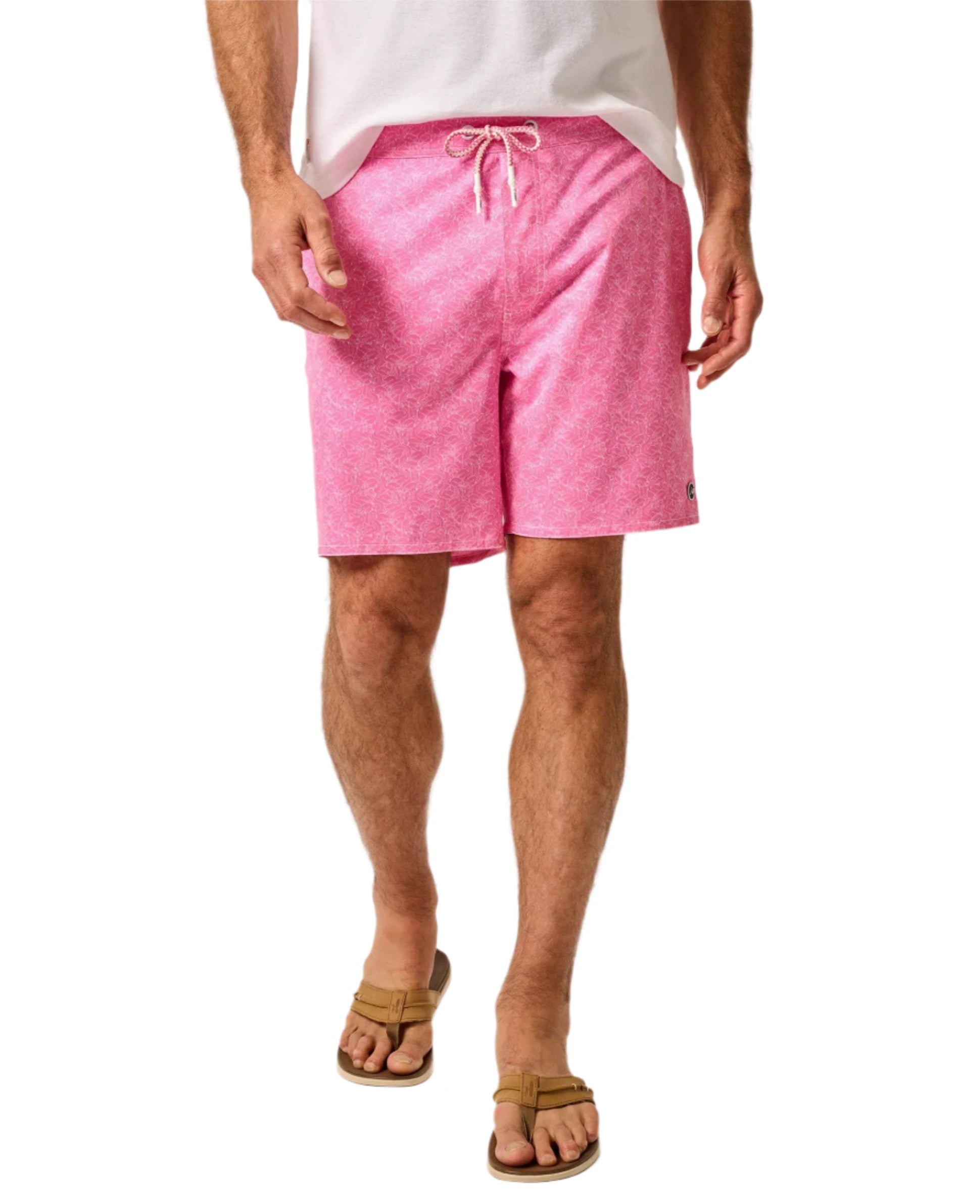 A person wearing Johnnie-O Tickled Pink Swim Trunks, a white shirt, and brown sandals.