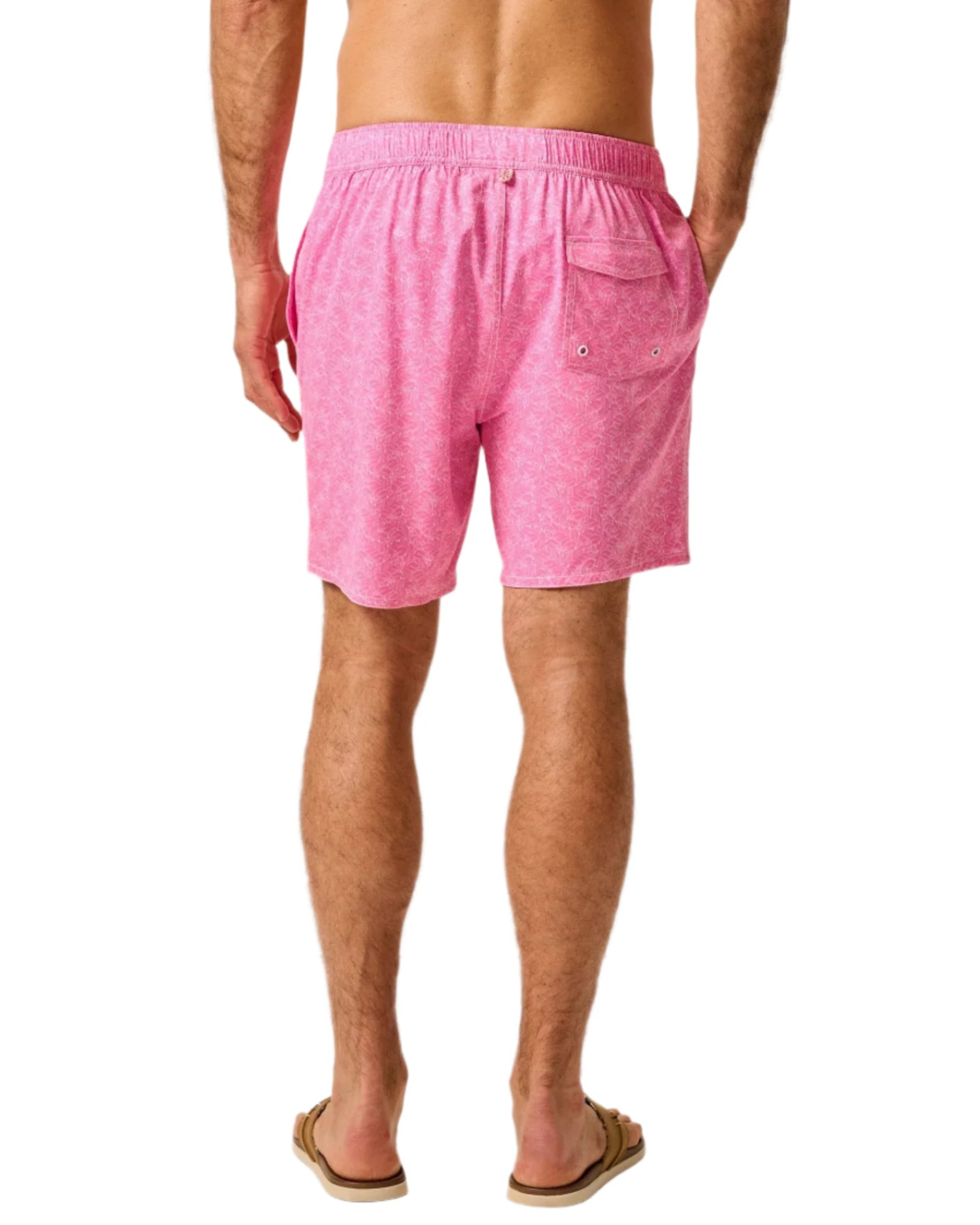 A person is shown from behind, wearing Johnnie-O Tickled Pink Swim Trunks and flip-flops, standing against a white background.