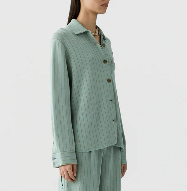 A woman wearing the Guest in Residence Pinstripe Work Shirt in light green with vertical stripes and matching loose-fitting pants, standing against a plain background.