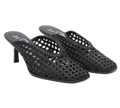 The ID Macrame Mule by 3.1 Phillip Lim features black handwoven faux leather, open backs, pointed toes, mid-height heels, and an architectural perforated pattern for a modern heeled mule look.