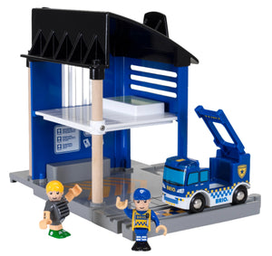 Introducing the BRIO World Police Station by Brio: a toy playset that includes a blue parking garage, a toy tow truck, two small toy figures, and a miniature police van ready to maintain law and order.