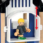 A toy figure featuring blond hair and green shoes is positioned inside the BRIO World Police Station, an imaginative blue and white playhouse by Brio. Red arrows suggest upward and downward movement, mimicking navigating through floors or possibly a daring escape from a tiny cell.