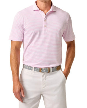 A man in a Johnnie-O Stetsons Polo, featuring light pink stripes and crafted from lightweight, moisture-wicking fabric with a collar and three buttons, stands with one hand in his pocket while wearing white pants. His belt showcases a geometric design.